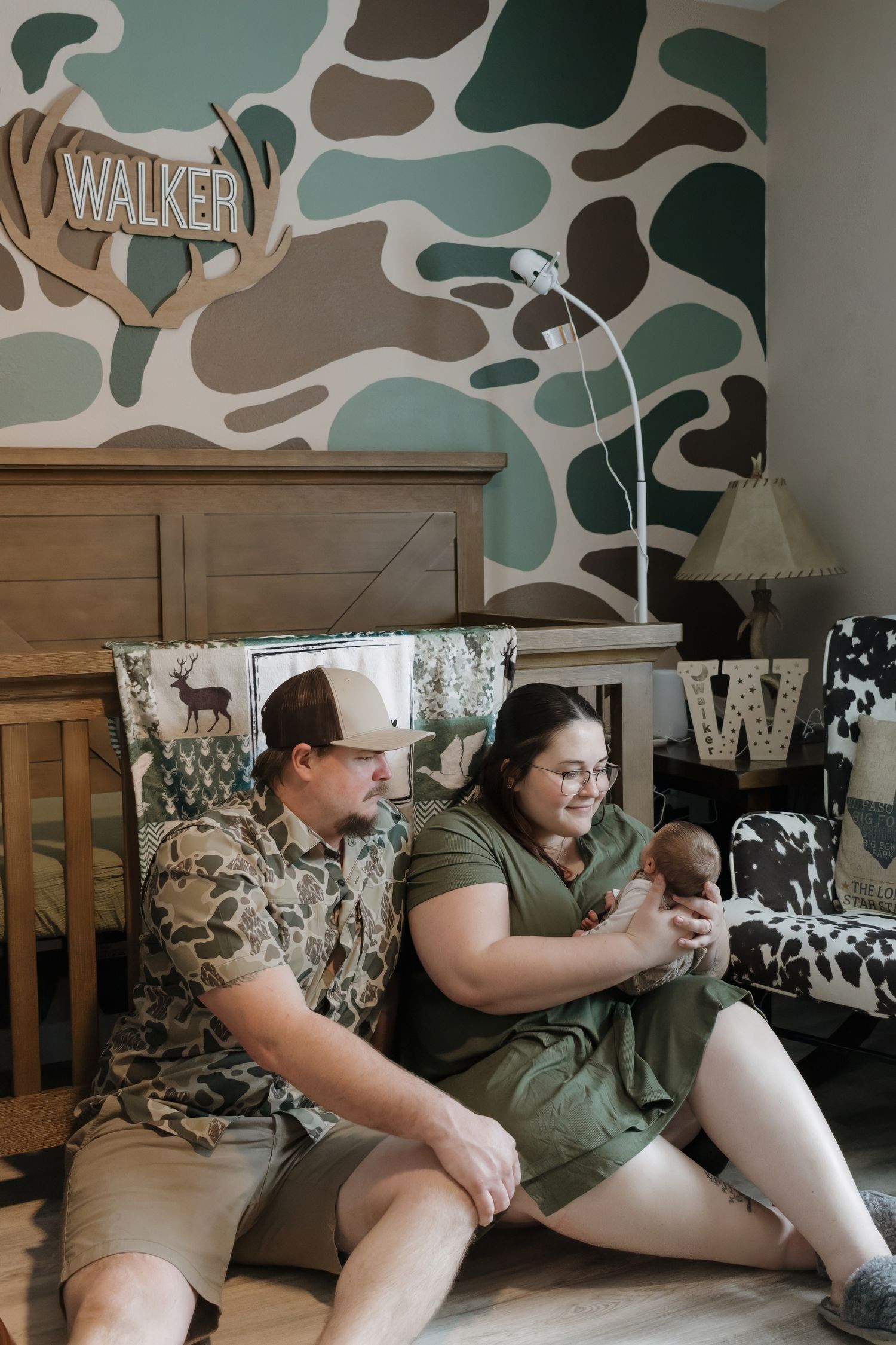Bedroom interior with camouflage themed decor and wall art featuring woodland animals.
