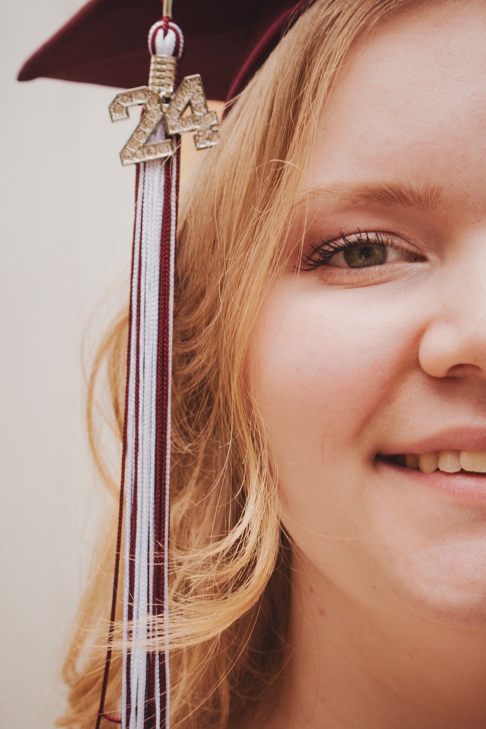 Close-up view of someone holding a graduation tassel against a light background.