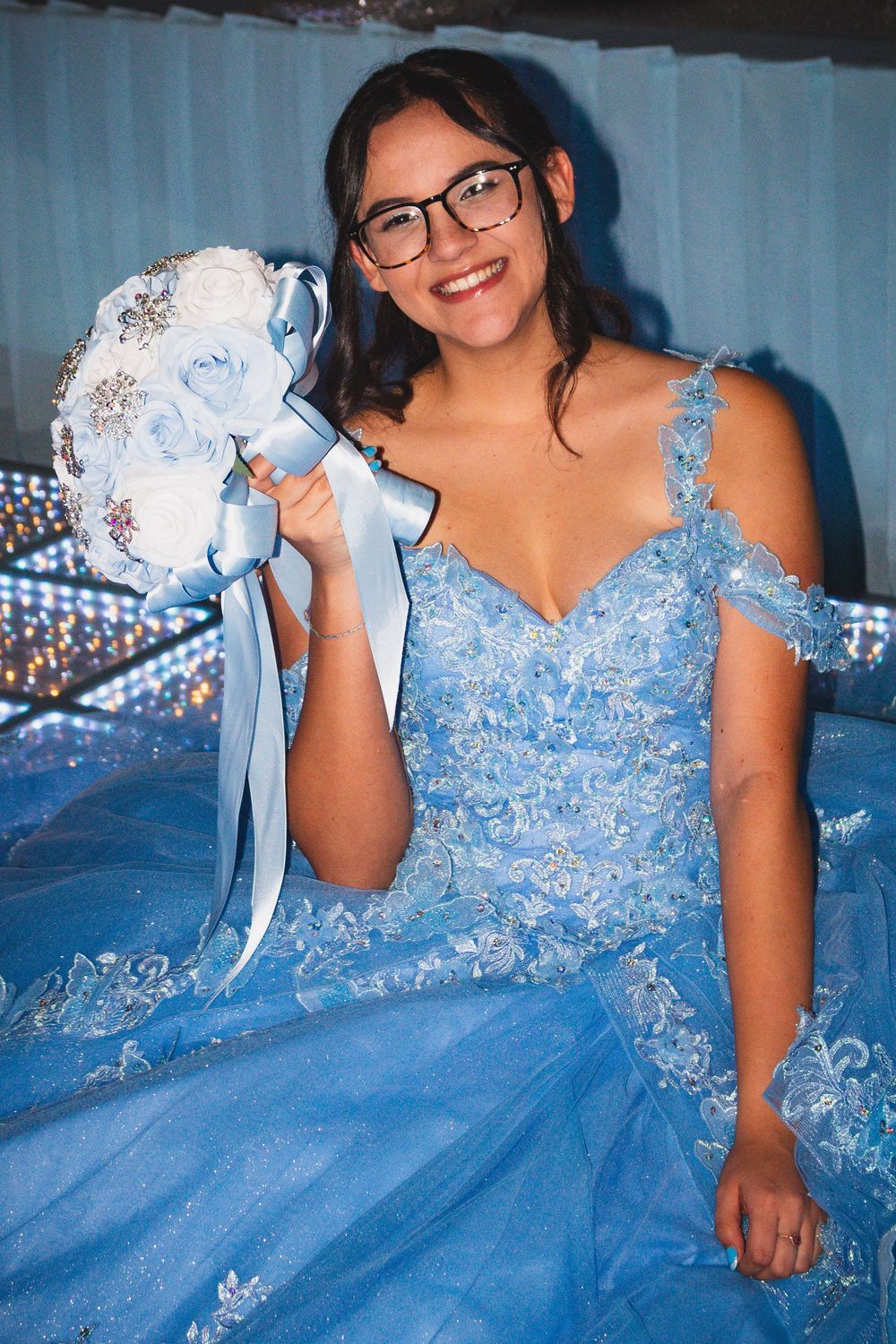 A quinceañera photo collage showing a person in a sparkly light blue ball gown holding a bouquet against a blue backdrop.