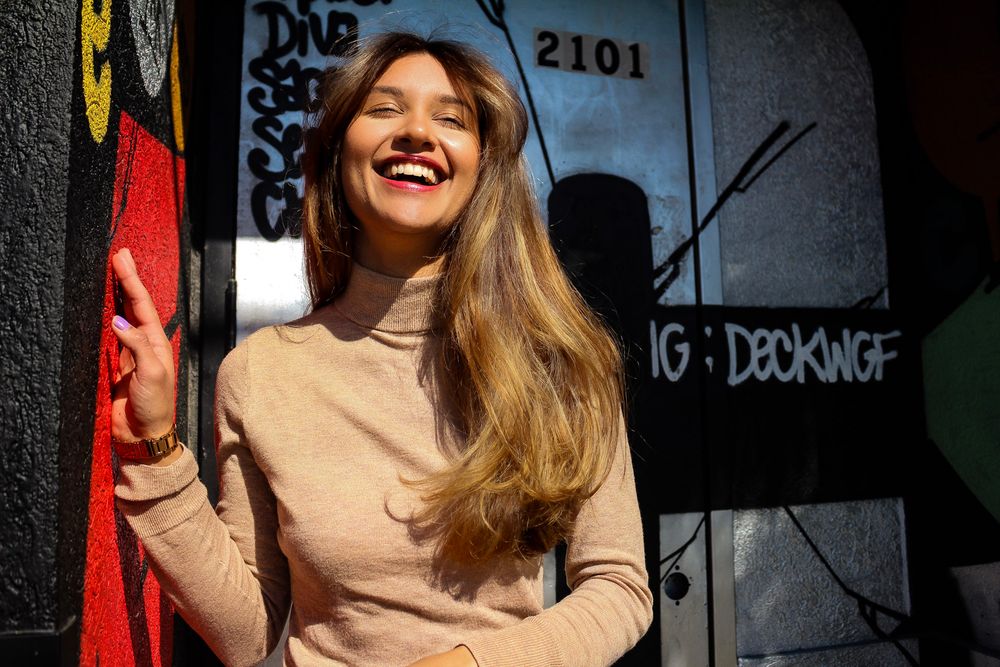A series of candid portraits showing joyful expressions and laughter against a dark wall with text and numbers.