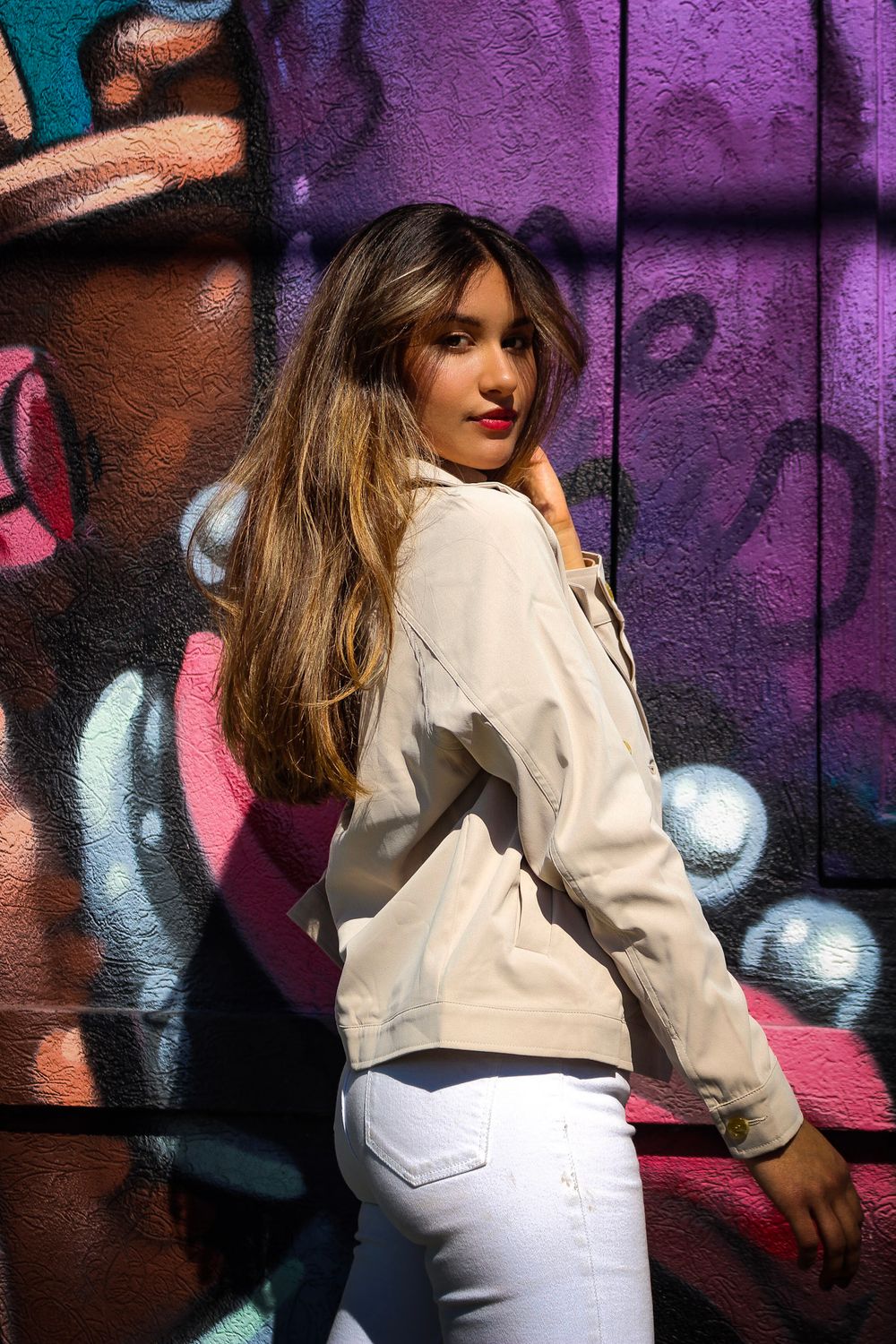 A person in a white outfit poses against a purple graffiti wall in a dynamic sequence of artistic shots.