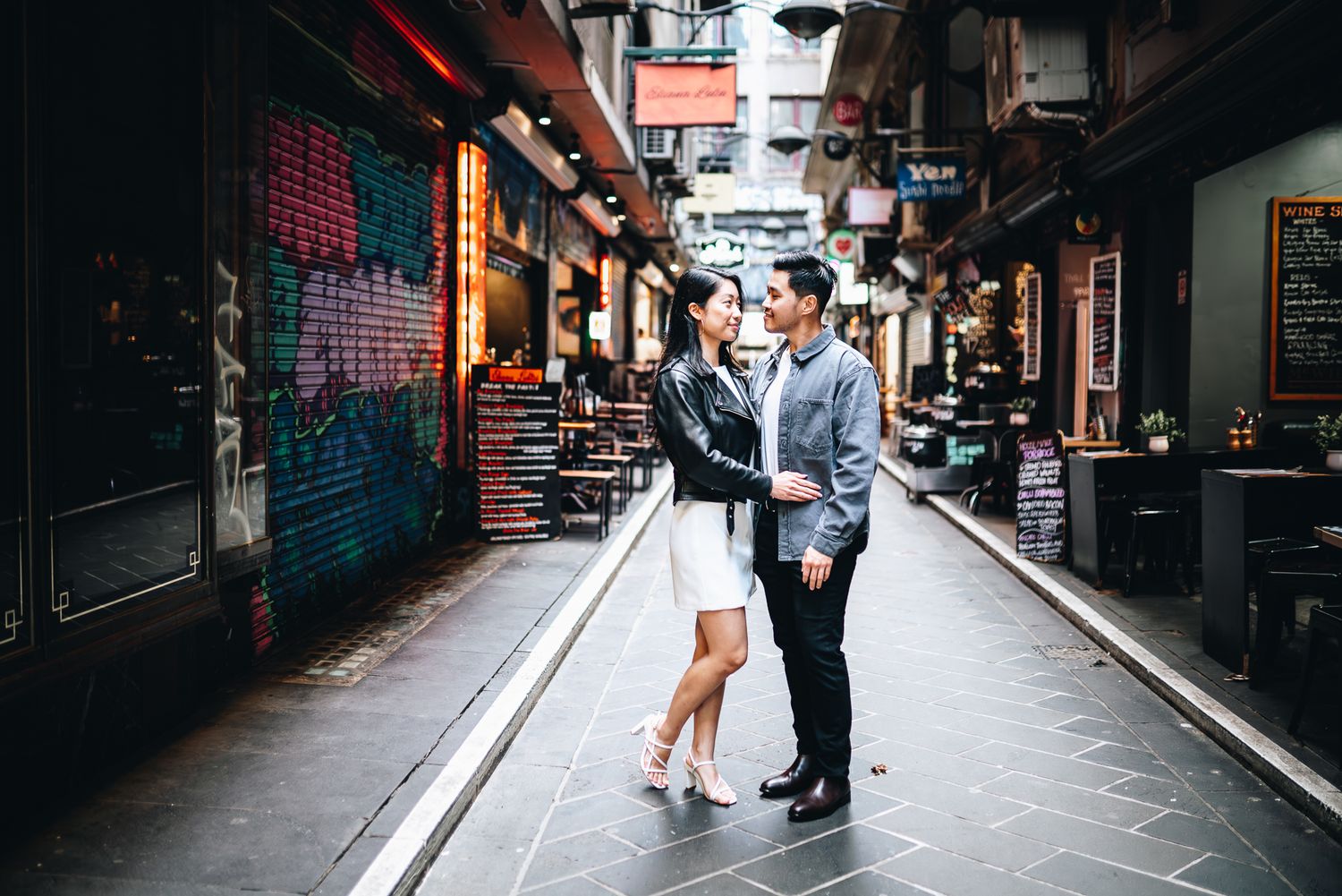 An engaged couple looking lovingly at each other in the middle of Mlebourne laneway taken by a Melbourne pre-wedding photographer.