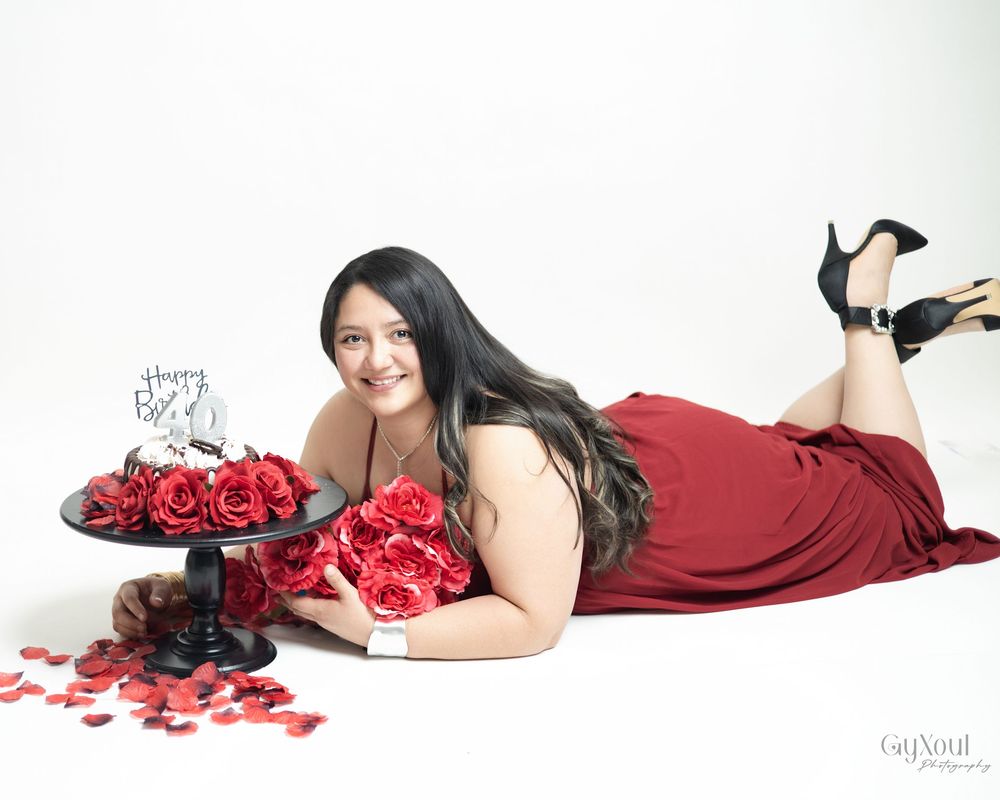 A romantic boudoir photo series featuring rose petals and burgundy fabric in an elegant white studio setting.