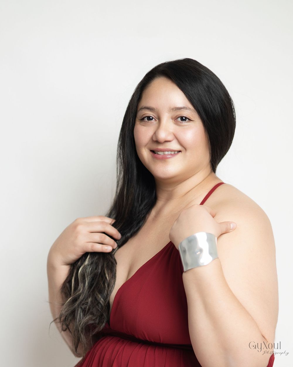 A woman in a burgundy dress poses against a white background in a series of connected portrait shots.
