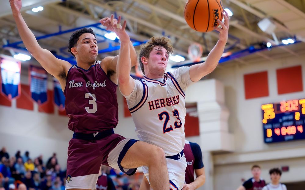 Trojans player goes up for a shot as two New Oxford defenders contest under the basket by SportsFox Photography, Hershey PA.