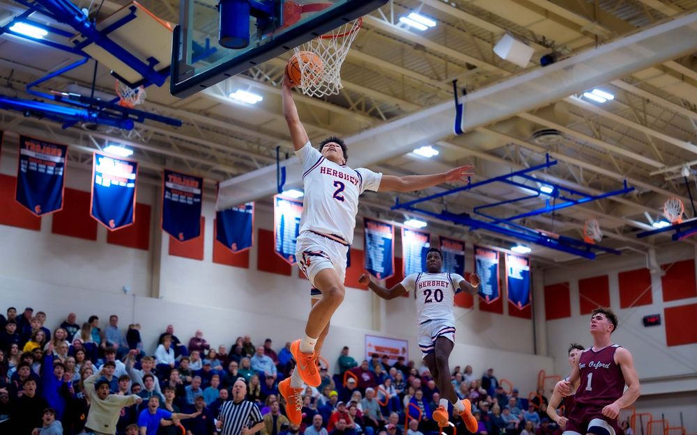 Trojans player leaps for a layup with New Oxford defenders and crowd in the background by SportsFox Photography, Hershey PA.