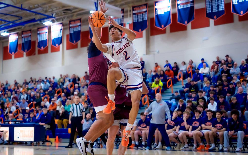 Trojans player goes up for a shot as a New Oxford defender contests in a packed gym by SportsFox Photography, Hershey PA.