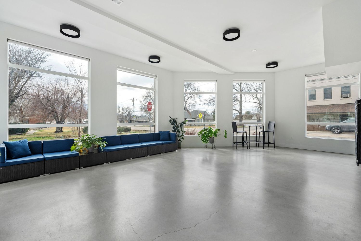 Modern open concept headshot photography space with white walls, large windows, and polished concrete floors.