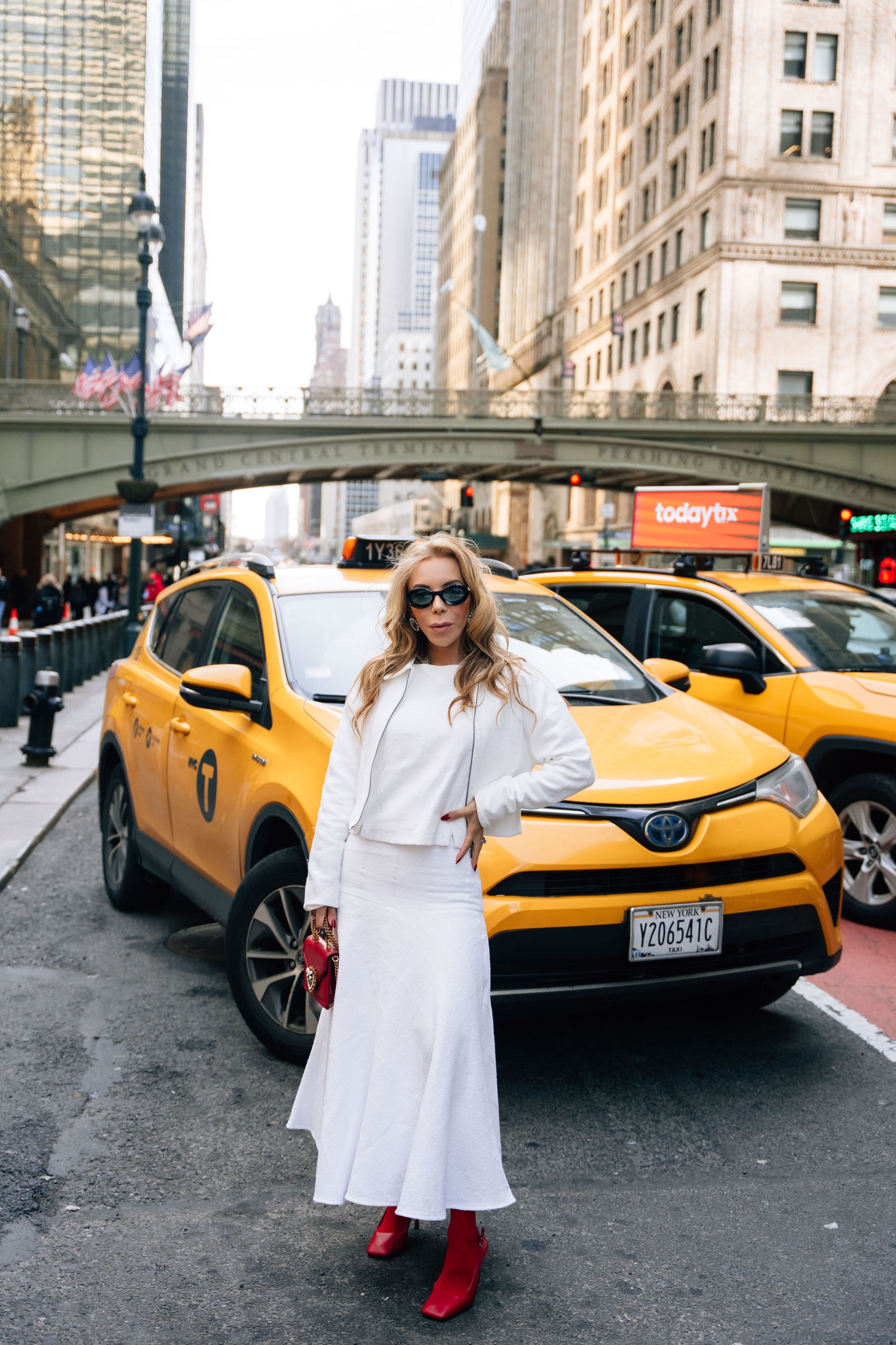 A series of photos showing a white dress and red boots against a yellow taxi on a busy New York City street.