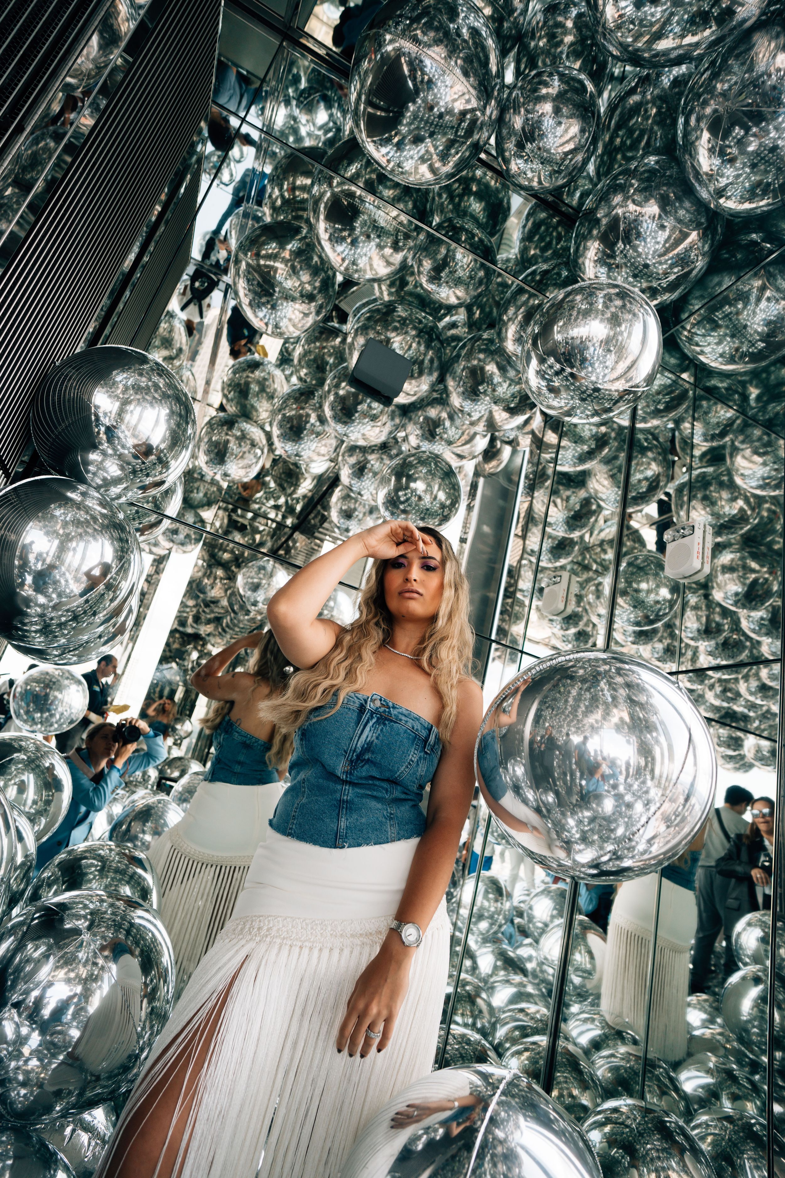 A sequence of photos showing a person in a white dress surrounded by hanging disco balls and mirrored surfaces.