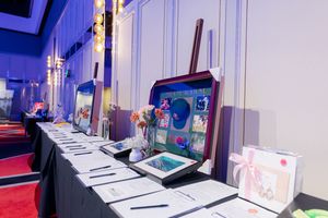 White display tables with merchandise and promotional materials set up at a corporate event.
