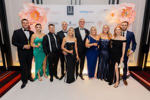 Group of people in formal attire posing together at an elegant event with floral decorations.