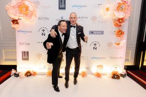 Event attendees gathering for photos at an elegant venue with peach-colored floral wall decorations.