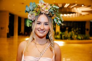 A floral crown adorned with greenery and blooms creates an elegant wedding accessory against a warm golden background.