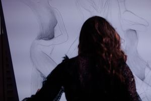 Silhouette of a person with long wavy hair against a light background with abstract smoke-like patterns.