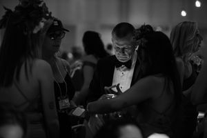 A black and white candid shot of guests interacting during an evening gala.