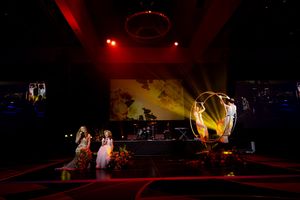 Concert stage illuminated with dramatic red spotlights and silhouetted performers.