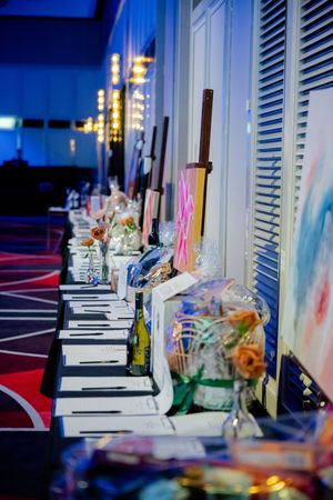 A table setting with wine bottles and decorations illuminated by blue and purple lighting at an evening event.
