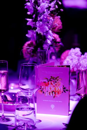 Elegant table settings with purple uplighting and floral centerpieces at a formal event.