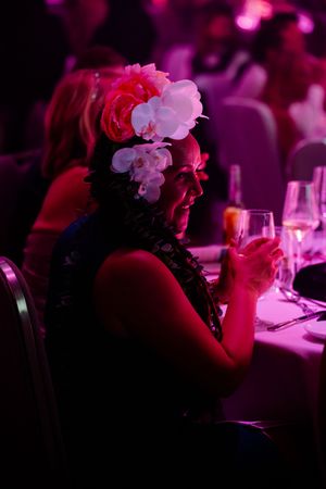 A dimly lit event scene with floral decorations and pink ambient lighting creating a romantic atmosphere.