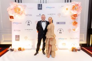 Event backdrop with sponsor logos and peach-colored floral arrangements.
