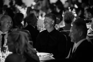 Black and white photo of guests mingling at a formal dinner event.
