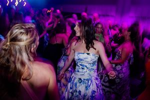 People dancing and celebrating at a nightclub with purple lighting and festive atmosphere.