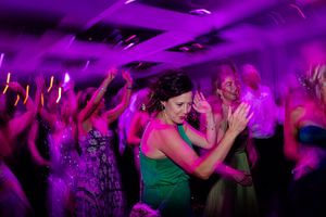 People dancing and celebrating at a nightclub with vibrant purple lighting and party atmosphere.