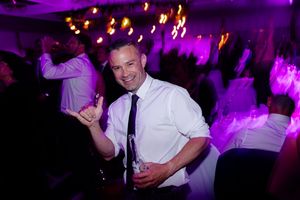A guest dances enthusiastically at a reception with purple lighting effects.