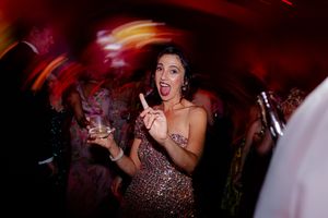 Energetic dance party scene with colorful lighting and guests dancing in evening attire.
