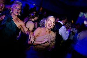 Energetic performers dancing and smiling under blue stage lights during a live entertainment show.