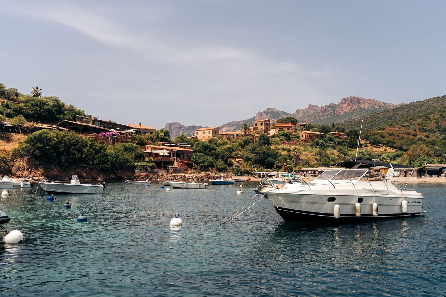 port de girolata avec bateau au premier plan et les petites maisons de pêcheurs en arrière-plan