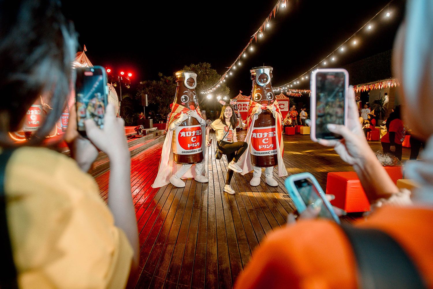 People dancing and celebrating at a lively party with string lights on a wooden deck.