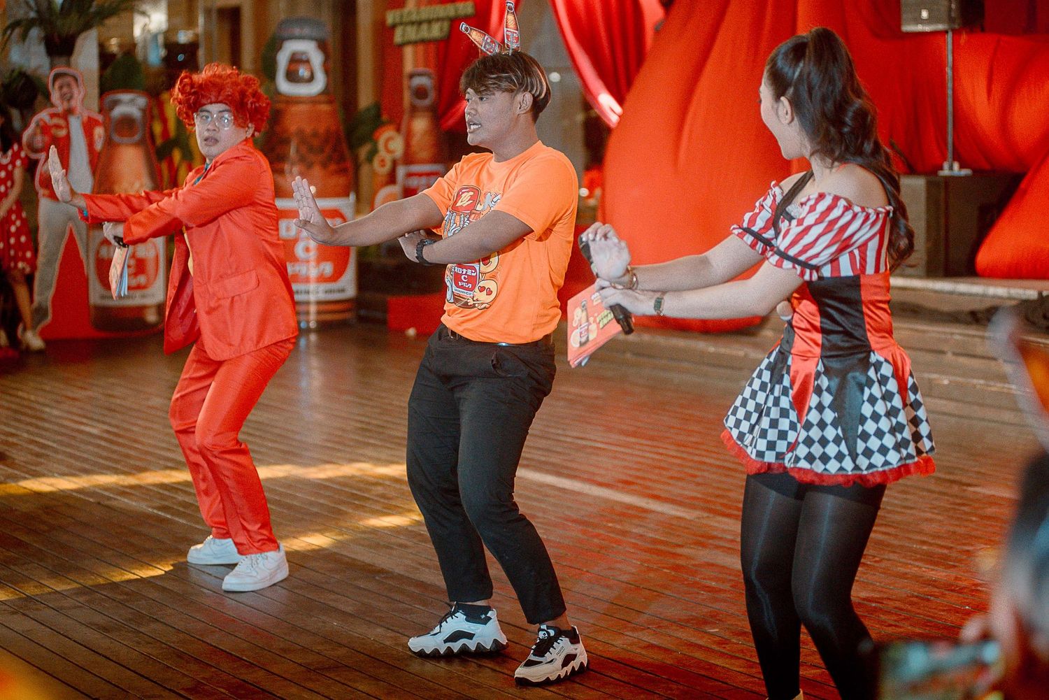 Dancers perform energetic swing dance moves on a wooden dance floor under warm lighting.