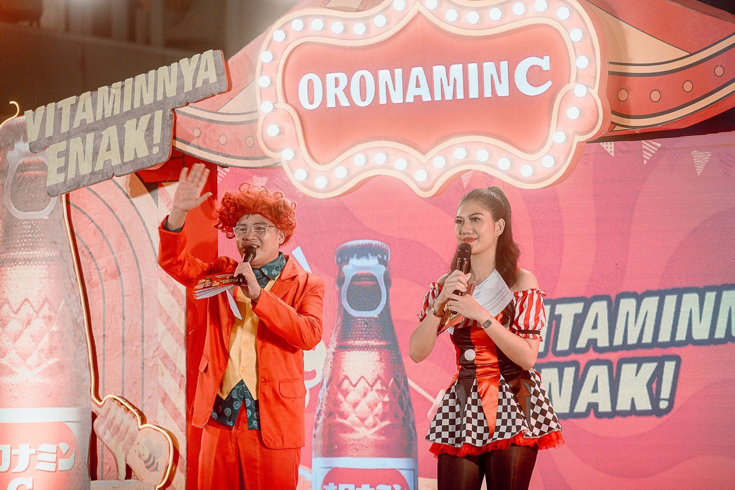 Pink-lit stage performance with neon signage and performers in vibrant costumes creating an energetic atmosphere.