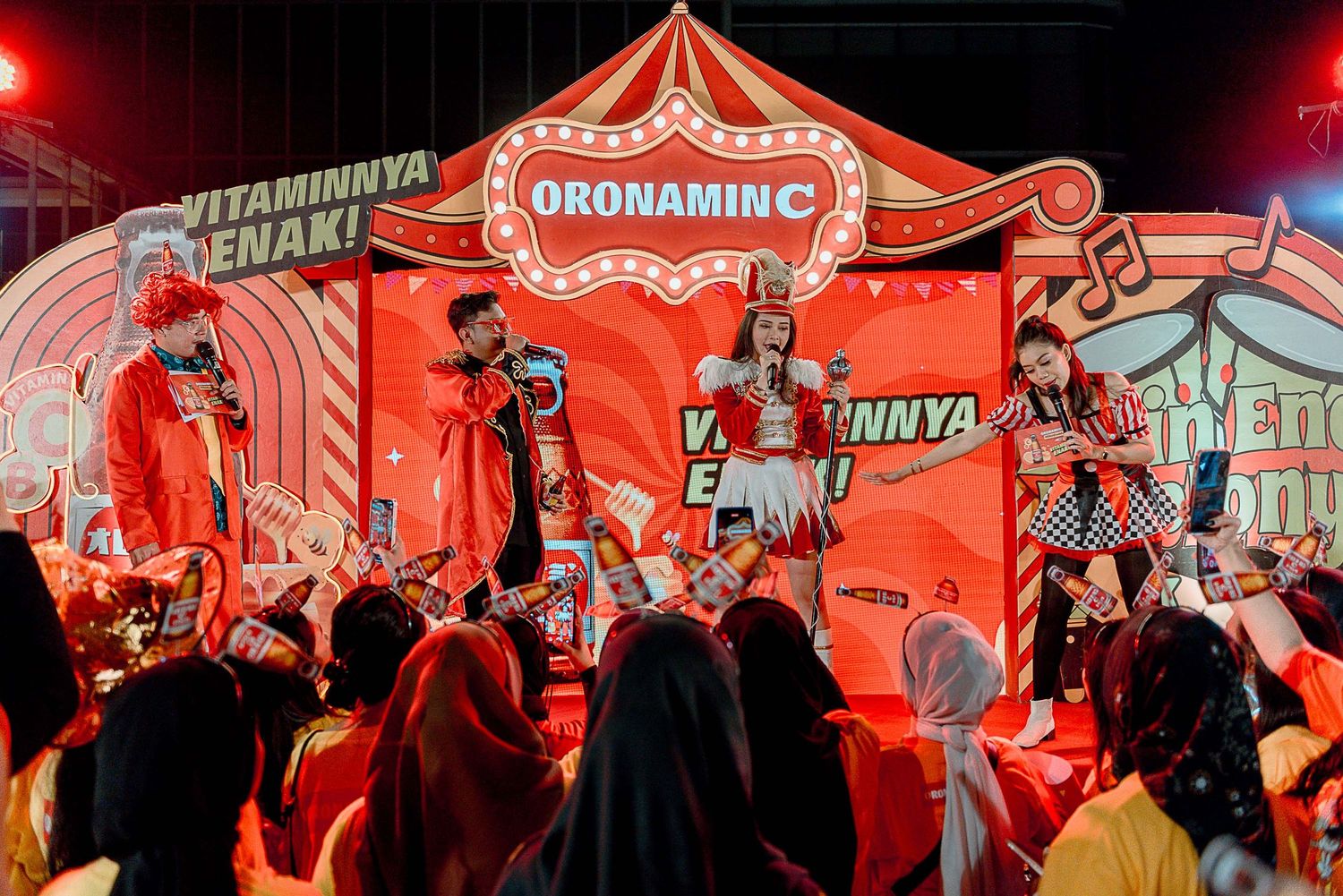 Red illuminated tent structures at night create a vibrant carnival or festival atmosphere with people gathering inside.
