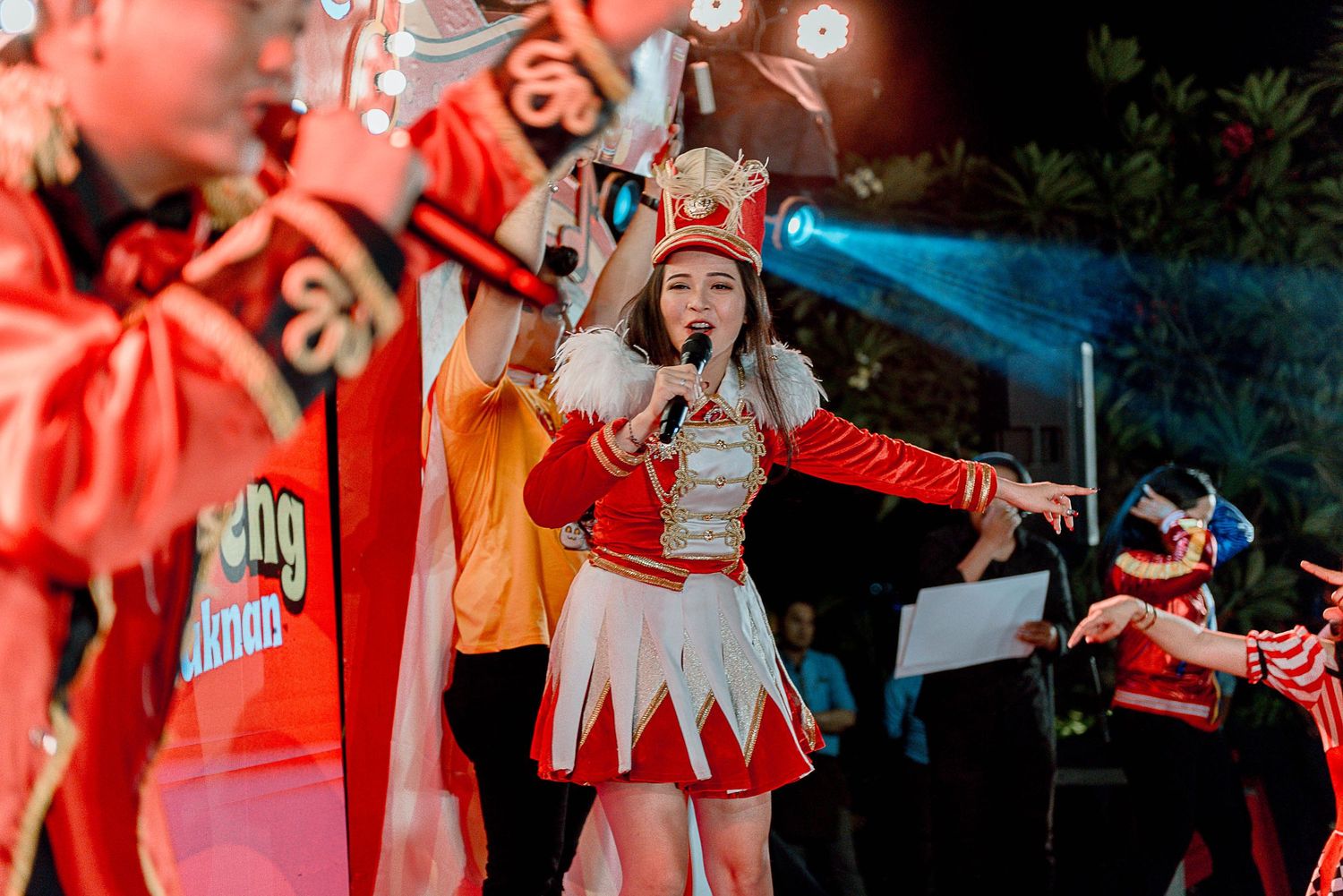 College cheerleaders in red uniforms perform synchronized dance routine during outdoor sporting event.