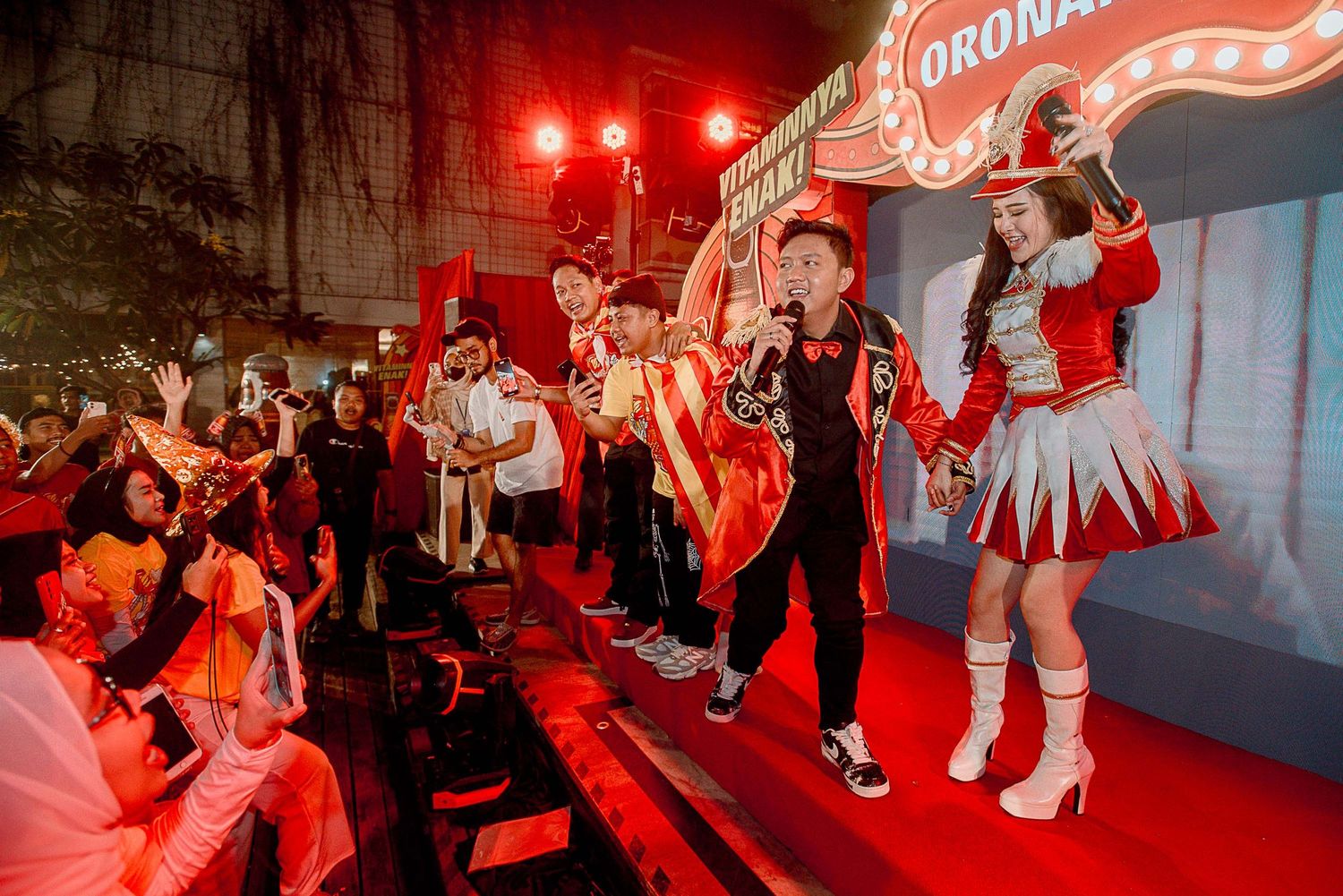 Dancers perform in traditional red and white costumes under dramatic red lighting during a stage performance.
