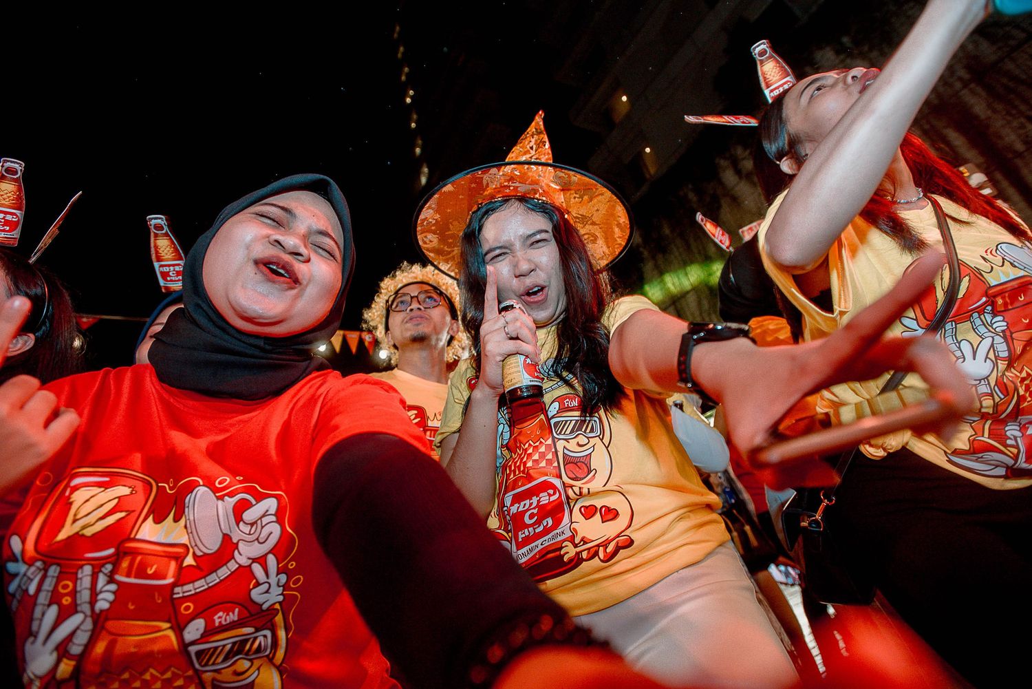 Energetic crowd at a concert venue with raised hands and colorful lighting creating an exciting atmosphere.