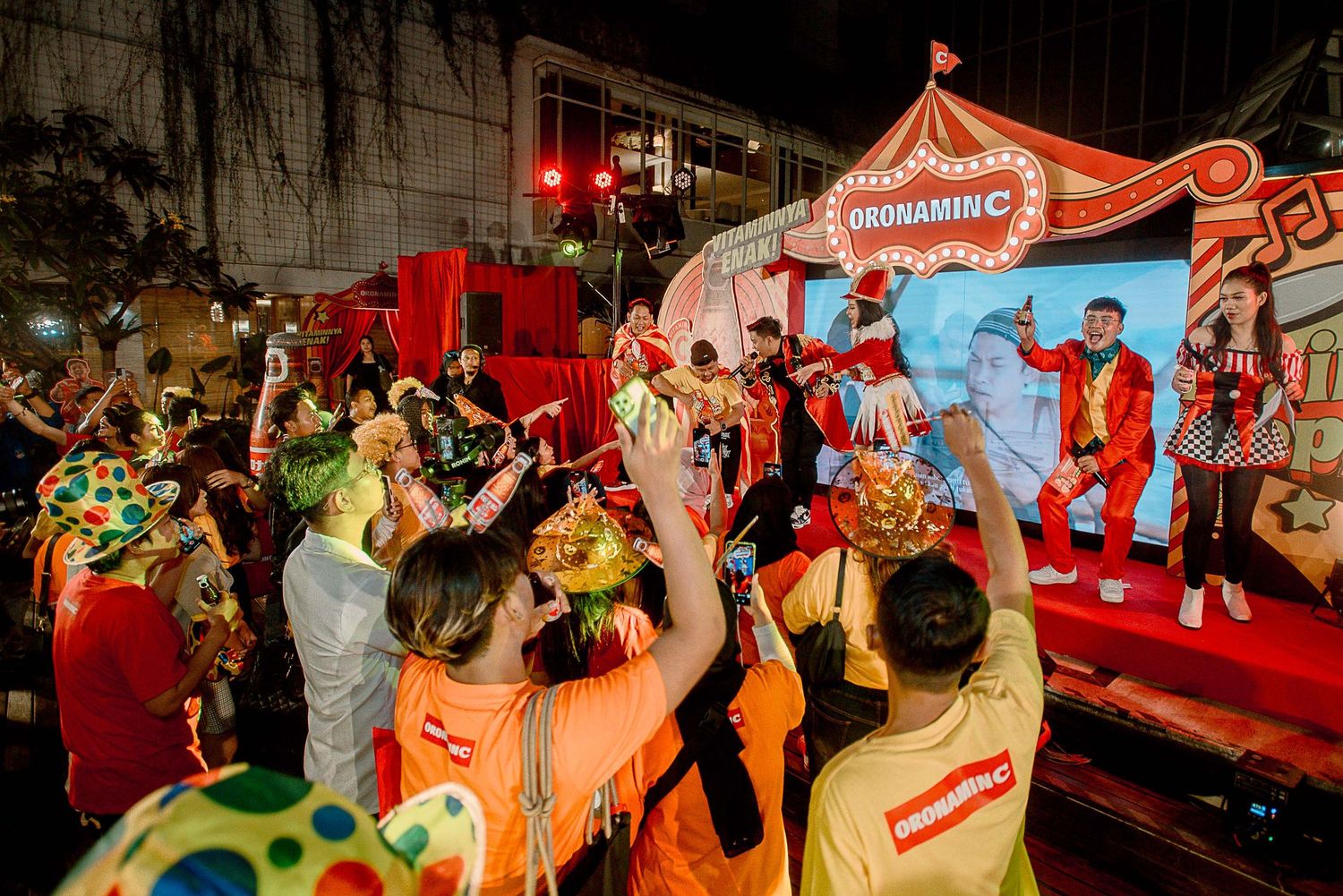 Crowd celebrates at vibrant Chinese New Year festival with colorful decorations and performers on illuminated stage.