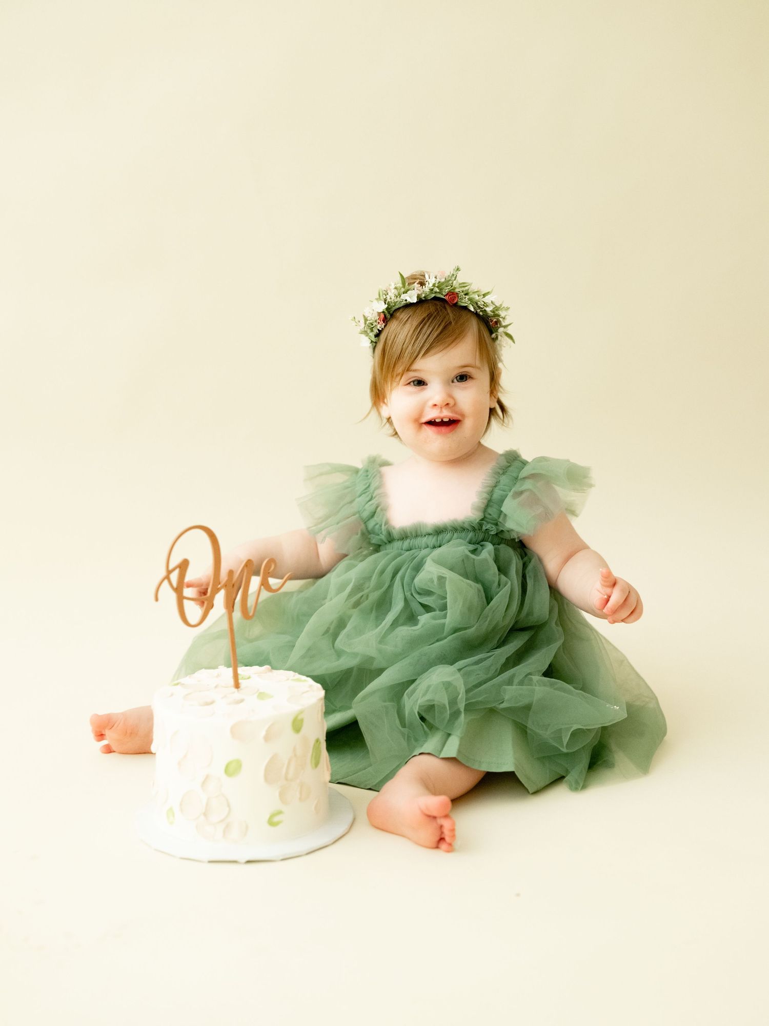 Baby in mint green tulle dress sits with birthday cake in a series of milestone celebration photos.