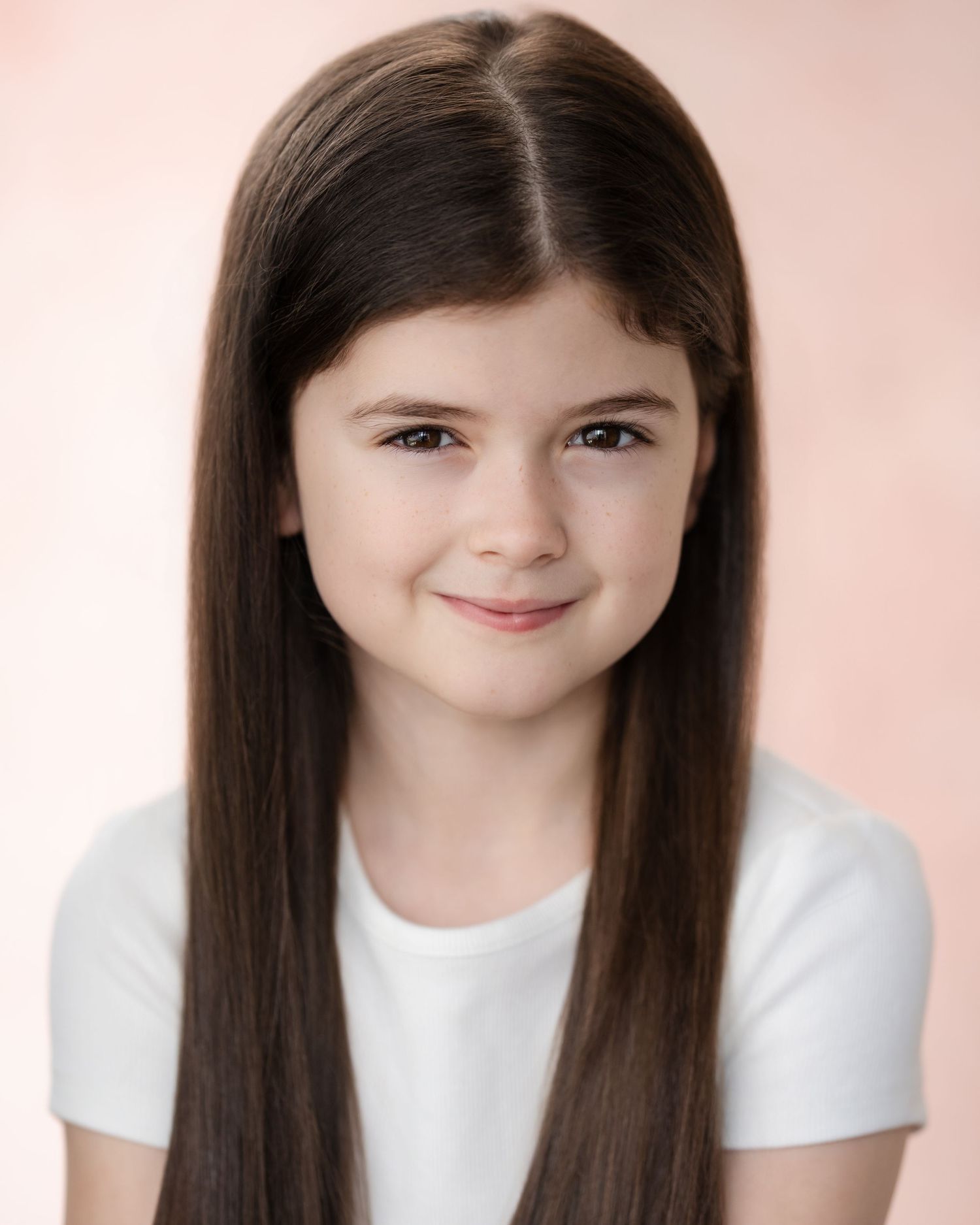 Four sequential studio portraits showing a young person with long dark hair and a white shirt against a soft pink backdrop.