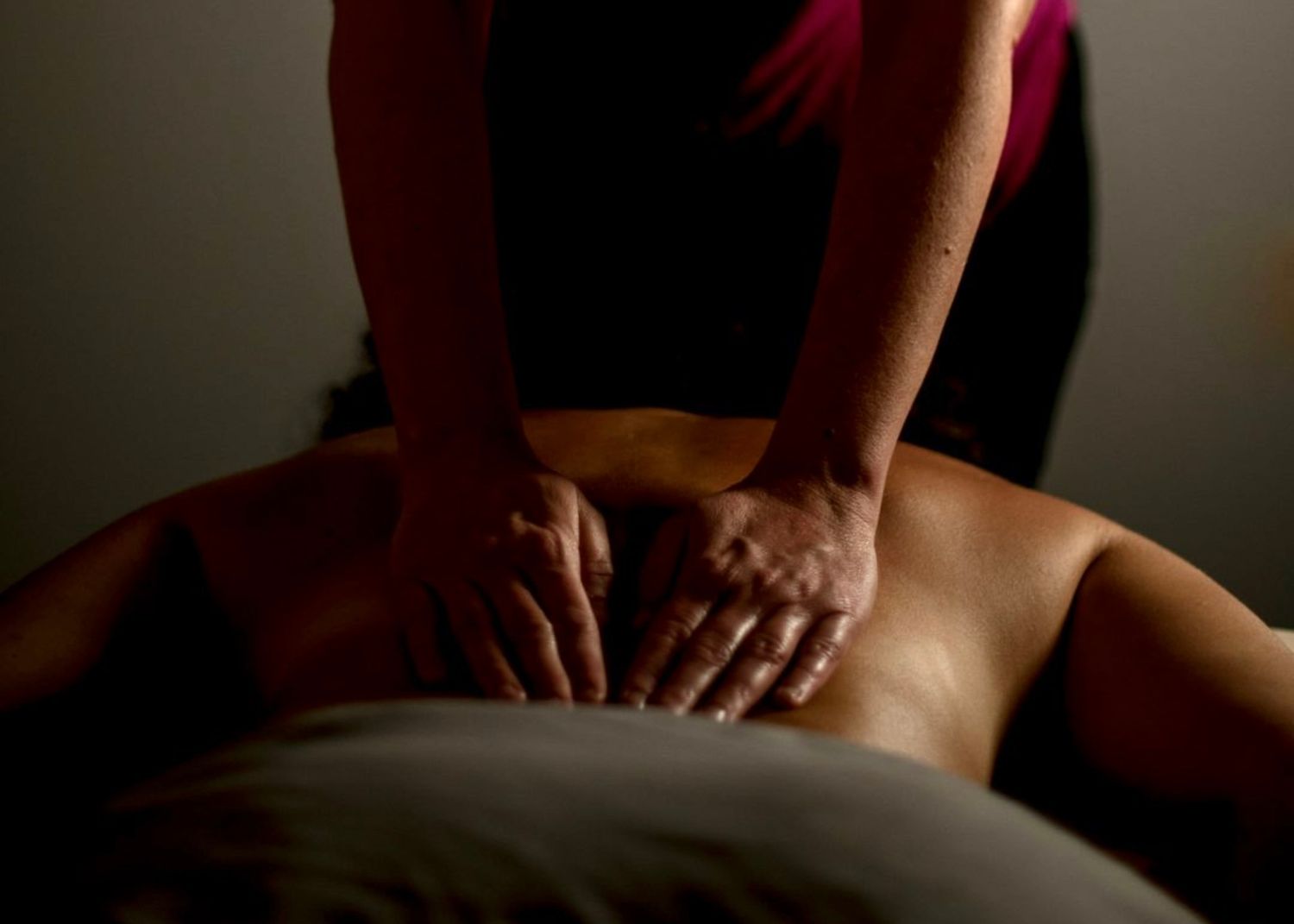 A massage therapist performs therapeutic massage techniques on a client's back in a dimly lit spa setting. in Wolverhampton by Birmingham