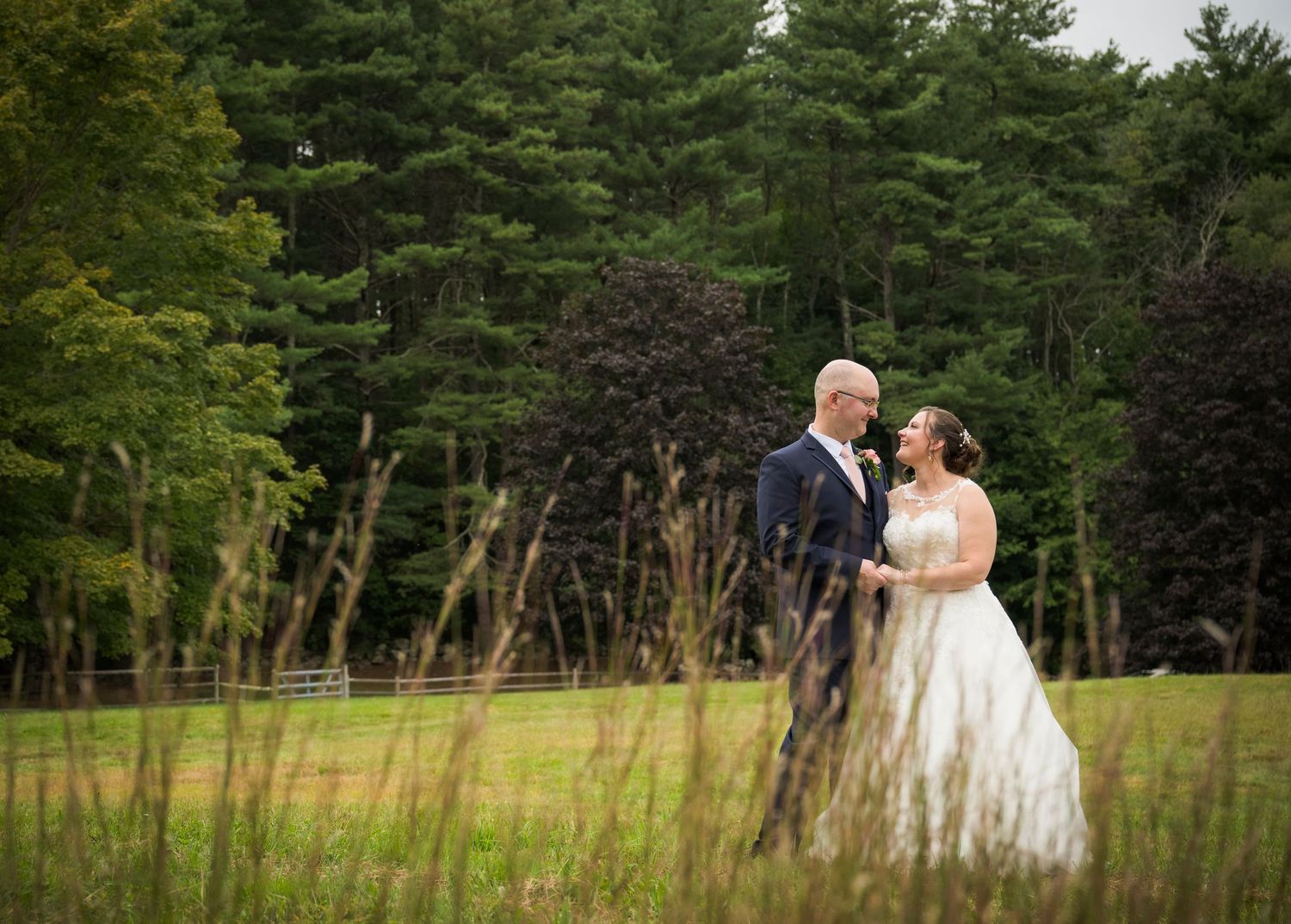 A romantic autumn wedding photo under a wooden pergola as a flowing white veil catches the breeze.