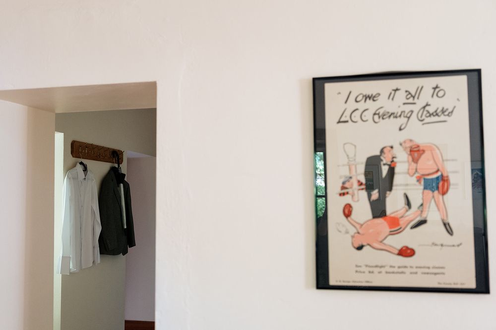 A vintage sports illustration poster hangs on a white wall next to a doorway with coats hanging inside.