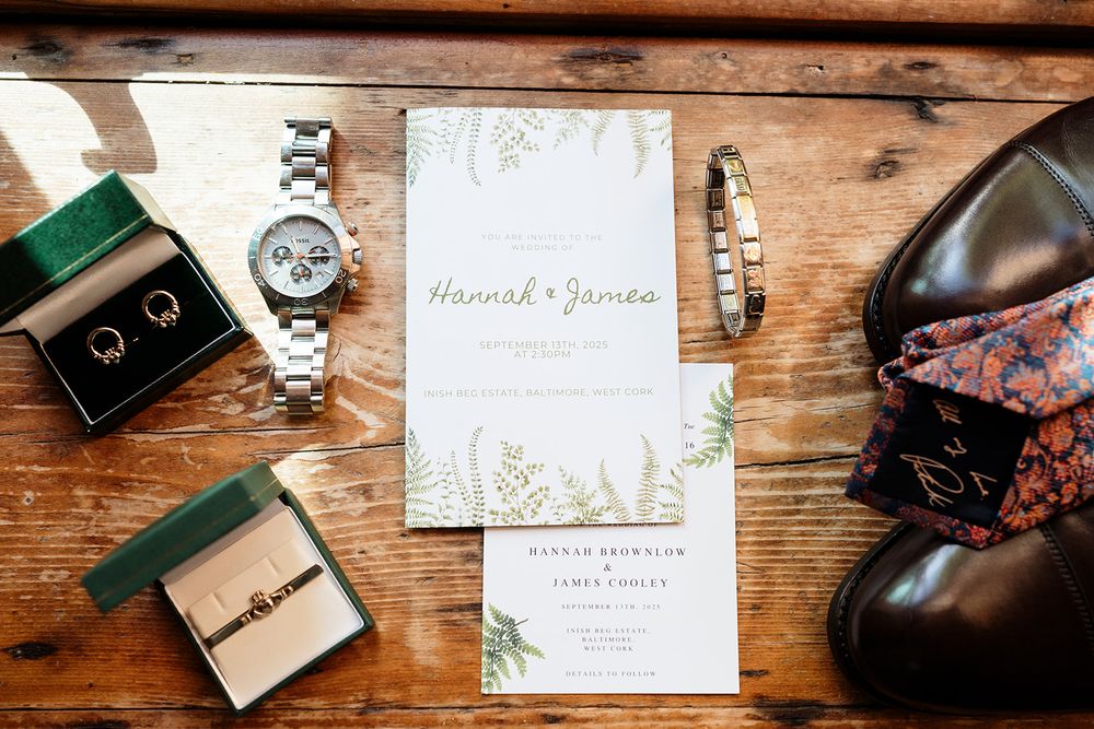 Wedding stationery and accessories artfully arranged on a rustic wooden surface with vintage camera and decorative elements.