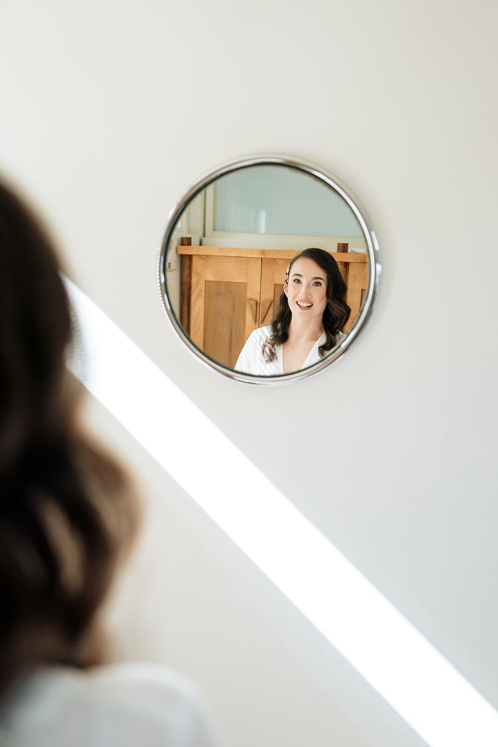 A series of four mirror reflections showing a figure in white against a light-colored wall.
