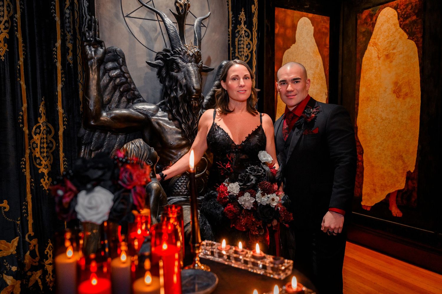 A dimly lit room with red candles and elegant table settings creates a romantic atmosphere at an evening event.