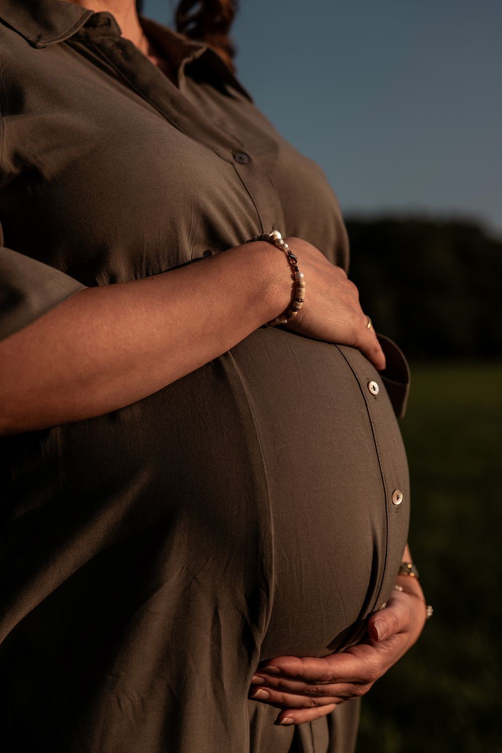 Nahaufnahme des Babybauchs mit den Händen der werdenden Mutter während einer Reportage.