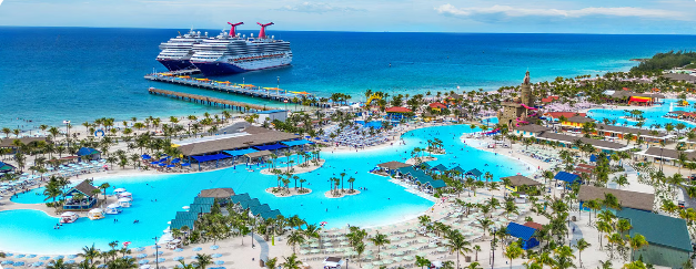 Aerial view of a massive turquoise lagoon pool with bridges and islands surrounded by resort buildings and palm trees.
